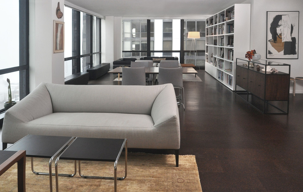 Immagine di un grande soggiorno moderno aperto con libreria, pareti bianche, pavimento in sughero, nessun camino e nessuna TV