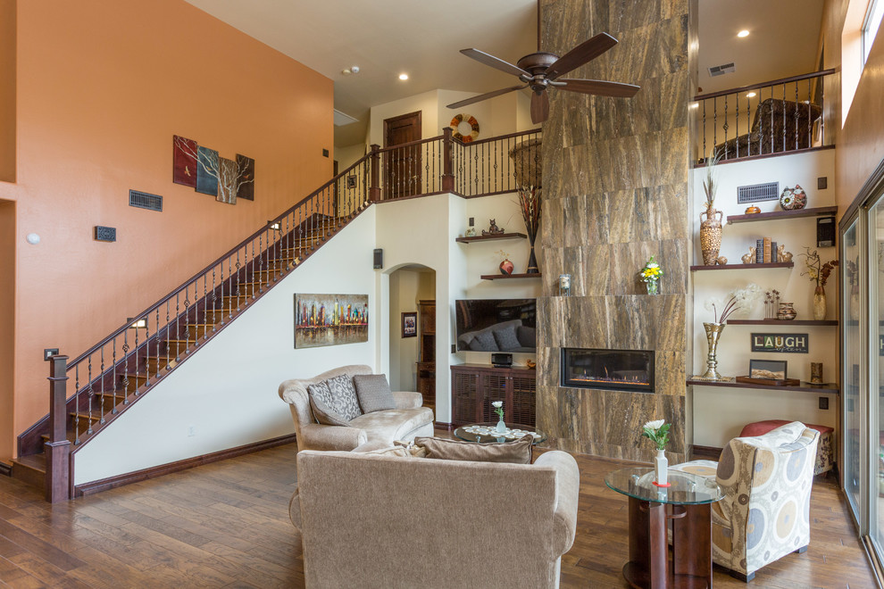 Cette image montre un salon traditionnel de taille moyenne et ouvert avec un mur beige, un sol en bois brun, une cheminée standard, un manteau de cheminée en carrelage et un téléviseur encastré.