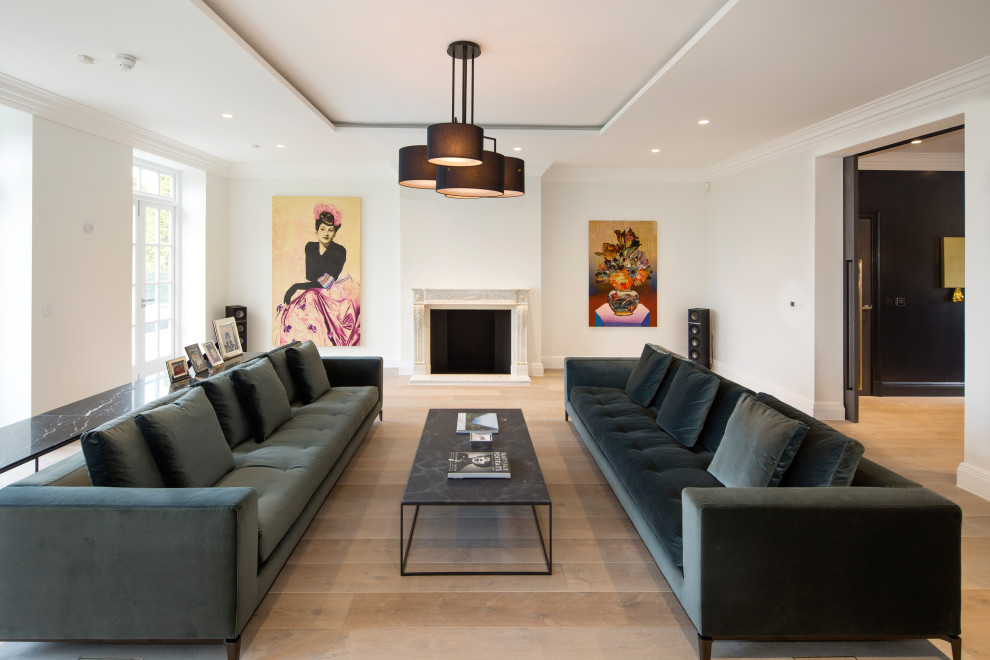 This is an example of a large contemporary formal open plan living room in London with white walls, light hardwood flooring and a standard fireplace.