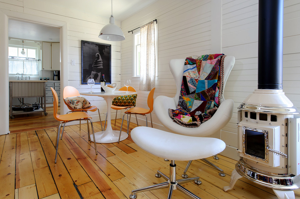 Immagine di un soggiorno boho chic con pareti bianche, pavimento in legno massello medio e stufa a legna