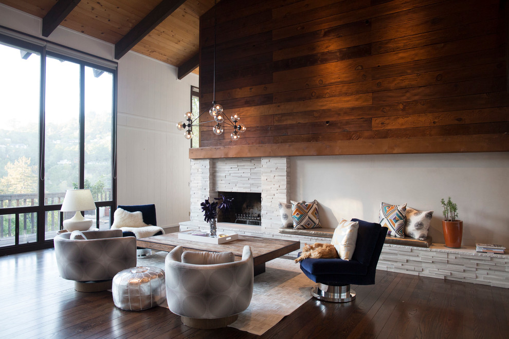 Cette photo montre un salon tendance avec une cheminée standard, un manteau de cheminée en pierre et éclairage.