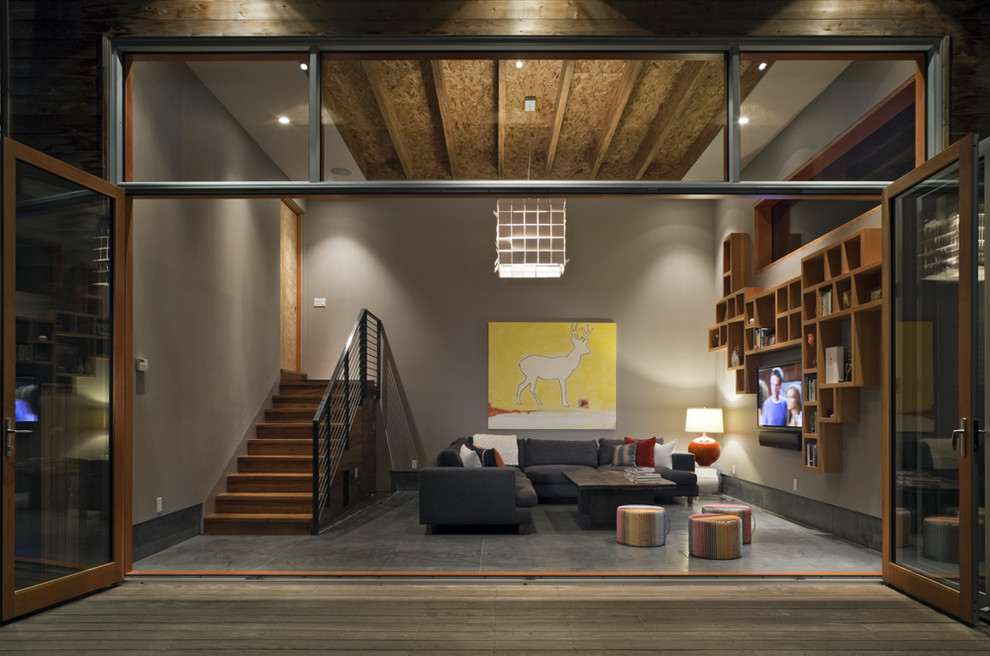 Идея дизайна: большая открытая гостиная комната в стиле модернизм с бетонным полом, коричневыми стенами и телевизором на стене без камина