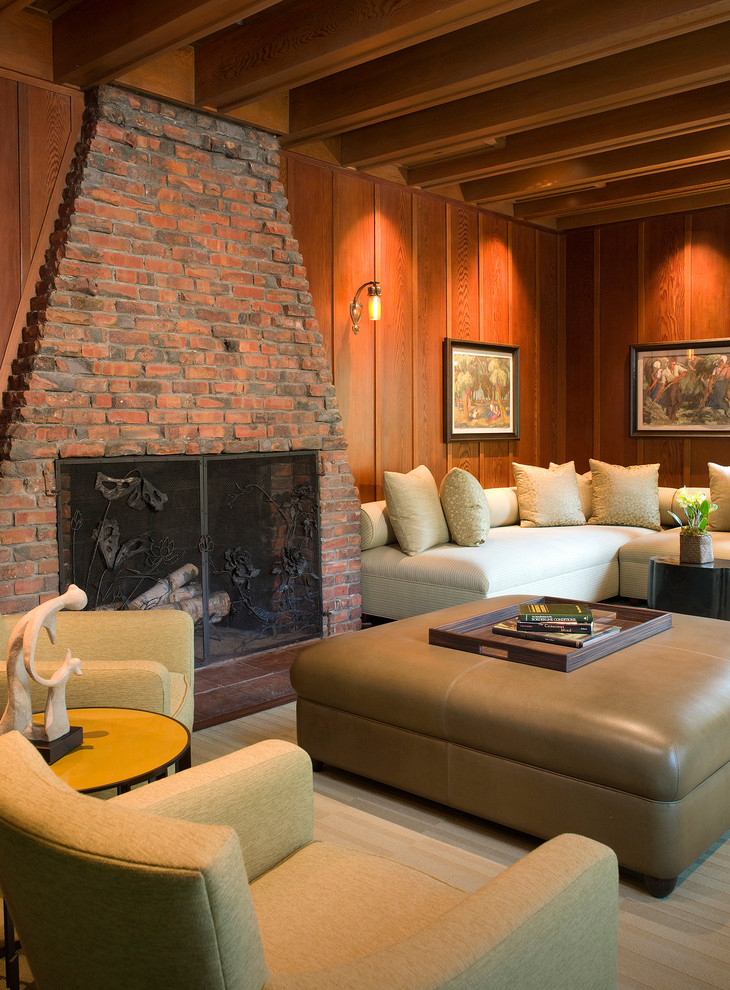 Exempel på ett stort klassiskt vardagsrum, med bruna väggar, mörkt trägolv, en standard öppen spis, en spiselkrans i tegelsten och en väggmonterad TV