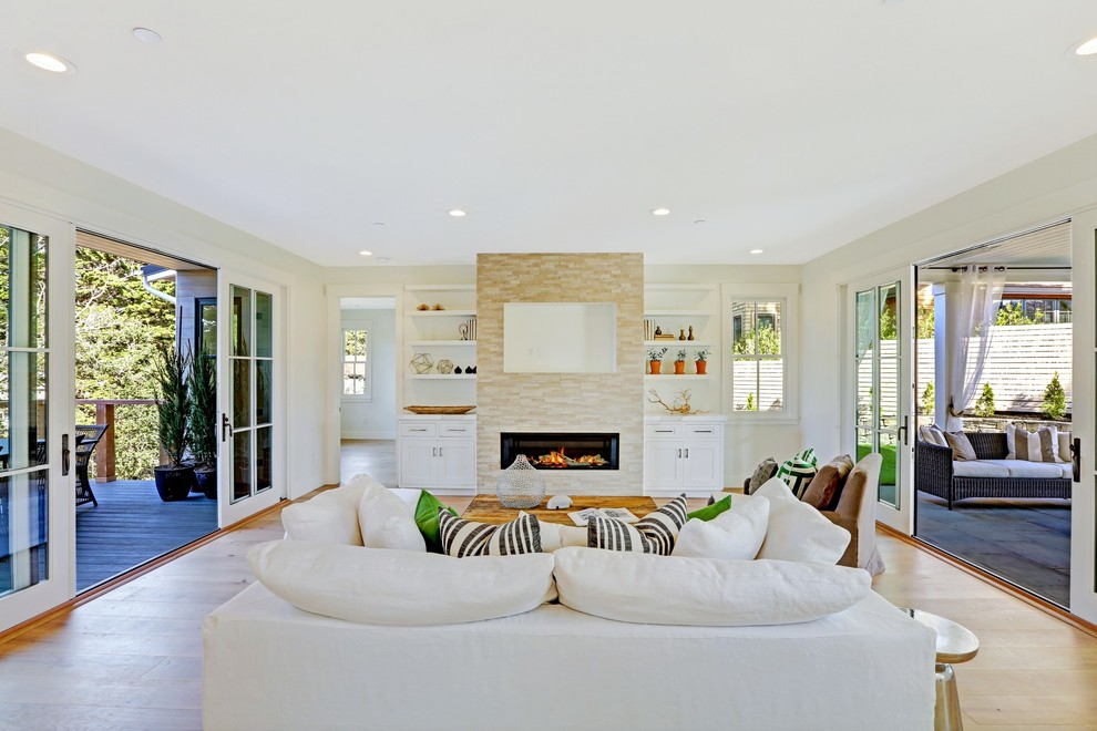 Landhausstil Wohnzimmer mit weißer Wandfarbe, hellem Holzboden, Kamin, gefliester Kaminumrandung, Multimediawand und braunem Boden in San Francisco