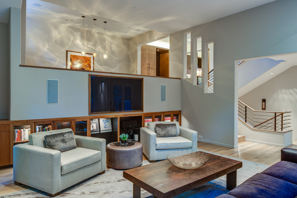 Diseño de salón cerrado contemporáneo con paredes azules, suelo de madera clara y televisor colgado en la pared