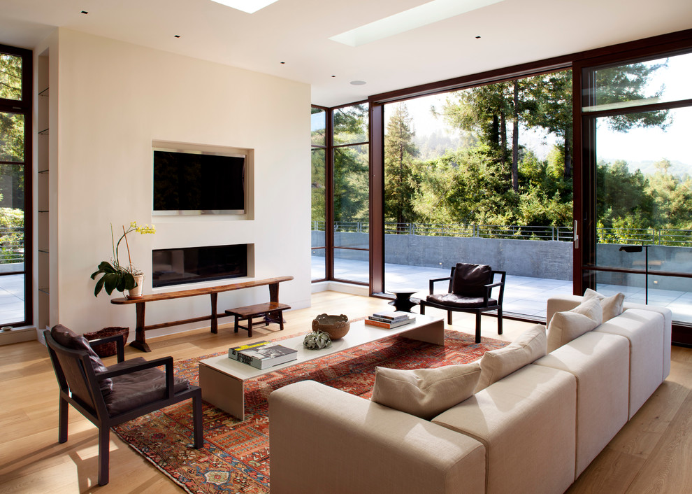 Cette image montre un salon minimaliste de taille moyenne et ouvert avec une cheminée ribbon, un téléviseur encastré, une salle de réception, un mur blanc, un sol en bois brun et un manteau de cheminée en plâtre.