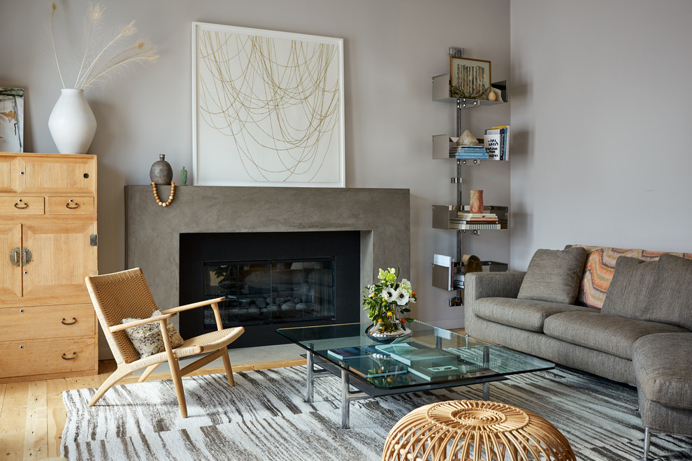 Aménagement d'un salon scandinave avec un mur gris, parquet clair, une cheminée standard et un manteau de cheminée en béton.