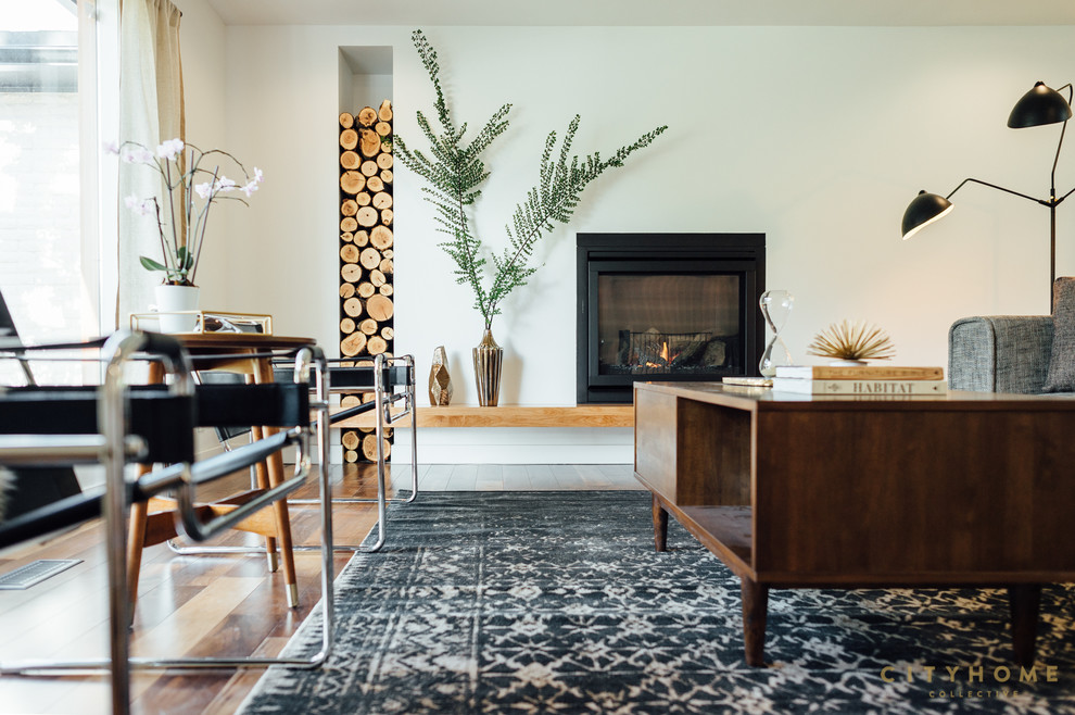 Immagine di un grande soggiorno minimalista aperto con pareti bianche, pavimento in legno massello medio, camino sospeso e pavimento marrone