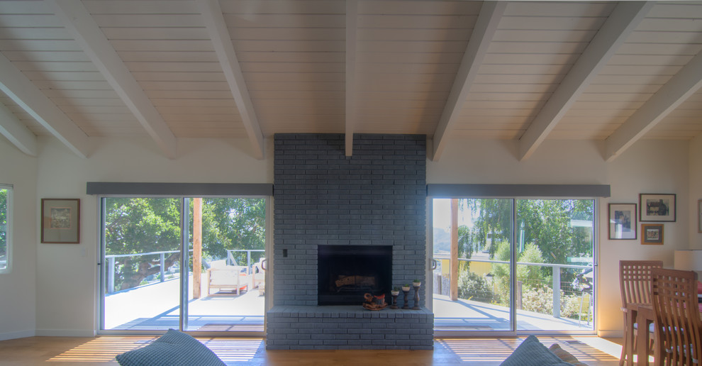 Mid-century modern open concept medium tone wood floor living room photo in San Luis Obispo with white walls, a standard fireplace and a brick fireplace