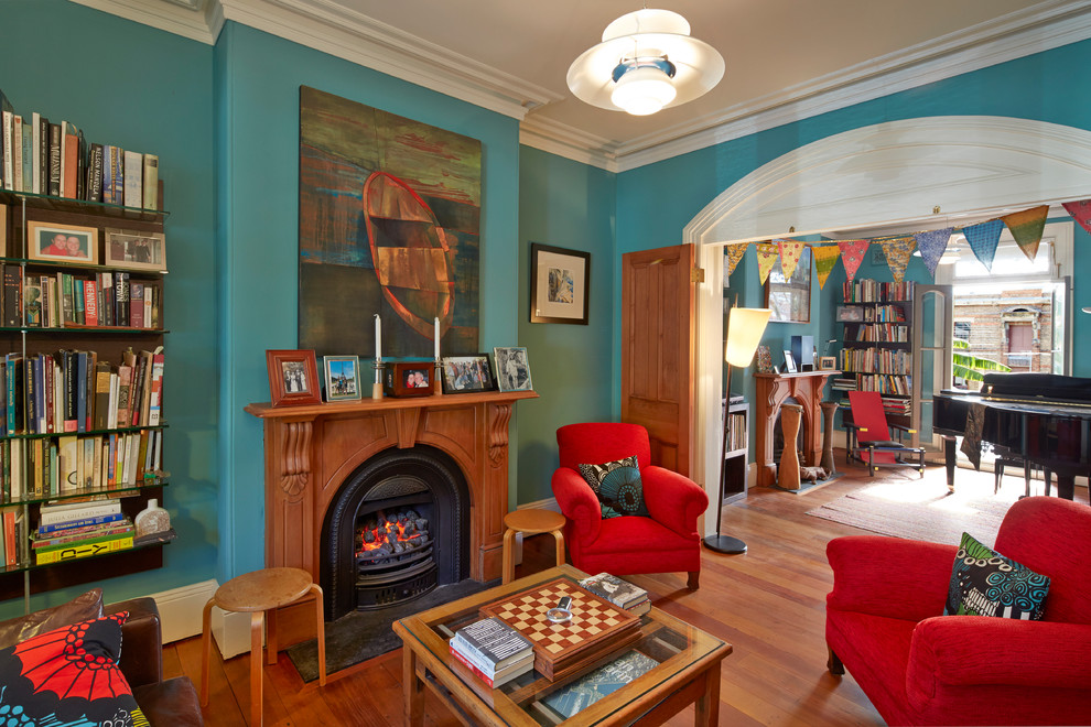 Idée de décoration pour un salon bohème fermé avec un mur bleu, un sol en bois brun, une cheminée standard et un manteau de cheminée en carrelage.