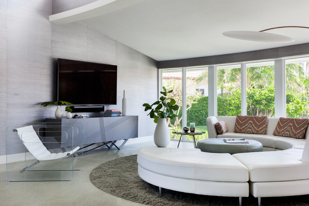 Источник вдохновения для домашнего уюта: большая открытая гостиная комната в стиле ретро с серыми стенами, телевизором на стене, серым полом и обоями за телевизором