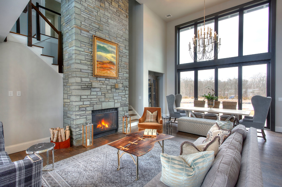 Cette photo montre un grand salon nature ouvert avec un mur gris, parquet foncé, une cheminée standard et un manteau de cheminée en pierre.