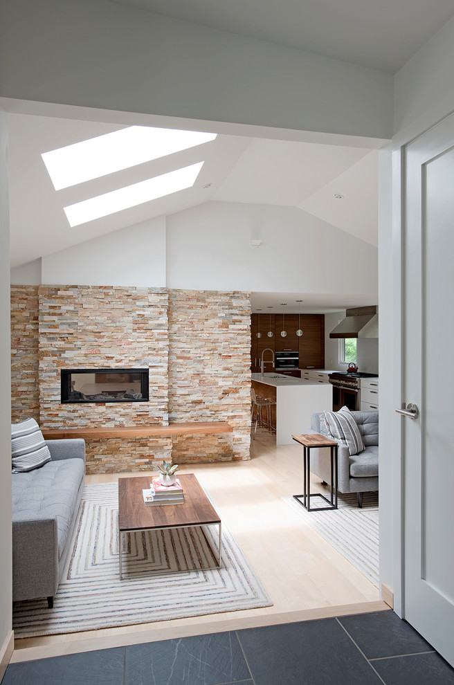 Idée de décoration pour un grand salon minimaliste ouvert avec un mur blanc, parquet clair, une cheminée double-face, un manteau de cheminée en pierre, un téléviseur fixé au mur et un sol beige.