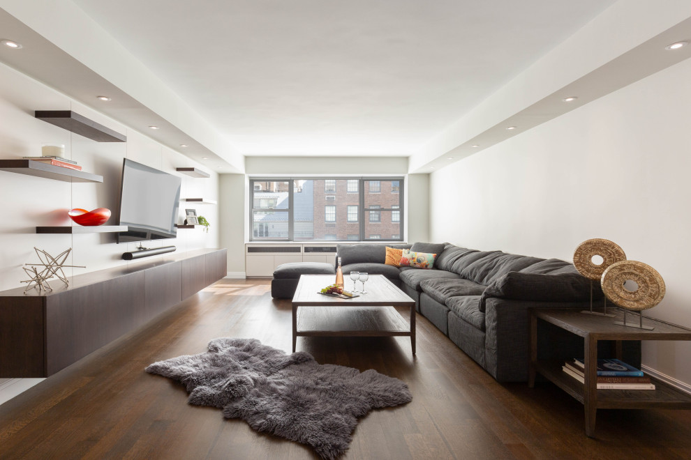 Photo of a modern living room in New York with white walls, medium hardwood flooring, a wall mounted tv and a drop ceiling.