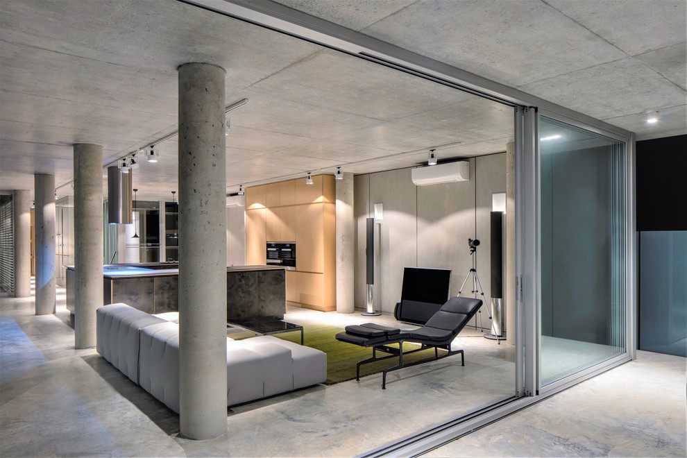 Idée de décoration pour un salon urbain ouvert avec un mur gris, sol en béton ciré, un sol gris et un téléviseur fixé au mur.