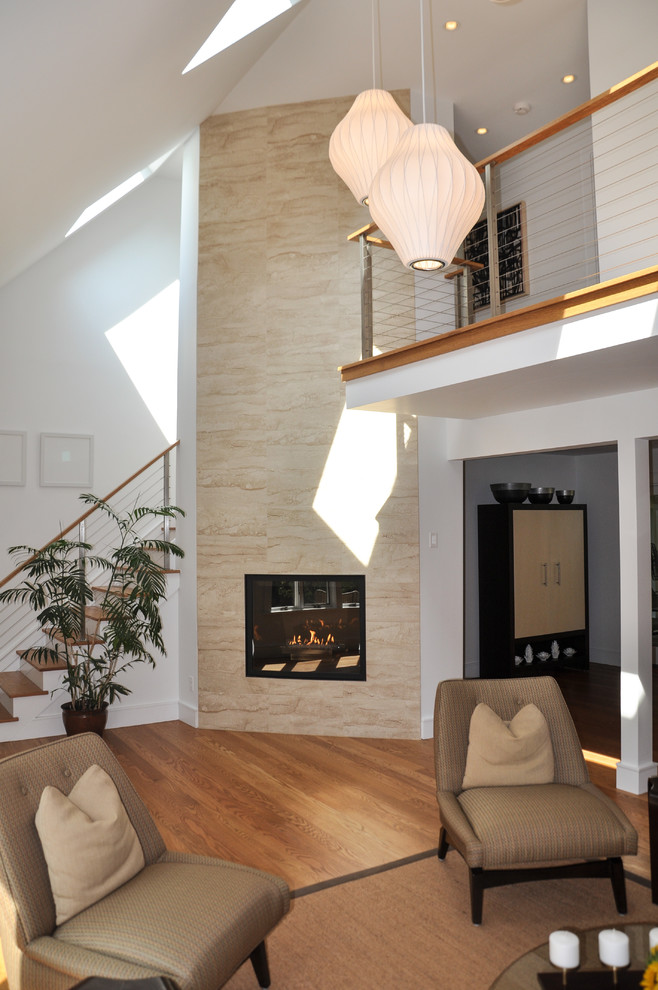 Idee per un soggiorno moderno con pareti bianche, pavimento in legno massello medio, camino classico e cornice del camino piastrellata