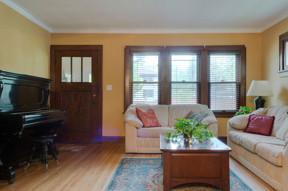 Kleines, Offenes Retro Wohnzimmer ohne Kamin mit gelber Wandfarbe, hellem Holzboden und verstecktem TV in Minneapolis