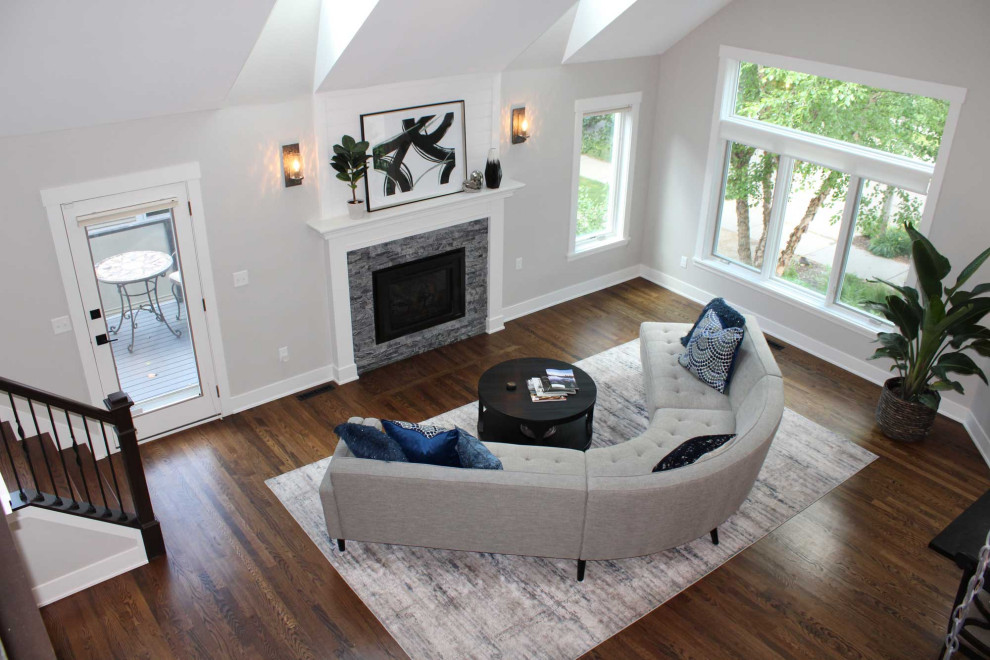This is an example of a medium sized contemporary open plan living room in Minneapolis with grey walls, dark hardwood flooring, a standard fireplace, a stone fireplace surround, brown floors and a vaulted ceiling.