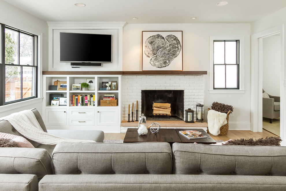 ミネアポリスにあるトランジショナルスタイルのおしゃれなリビング (白い壁、無垢フローリング、標準型暖炉、レンガの暖炉まわり、壁掛け型テレビ、茶色い床) の写真