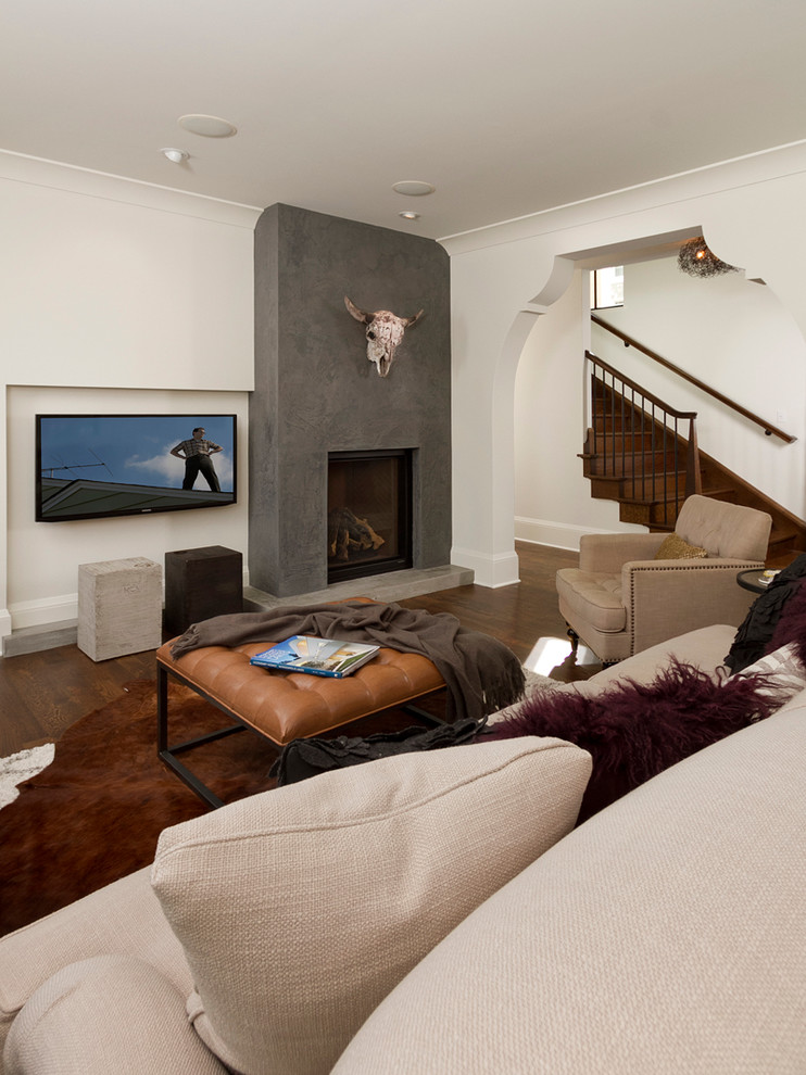 Immagine di un soggiorno chic chiuso con pareti bianche, parquet scuro, camino classico, cornice del camino in cemento e TV a parete