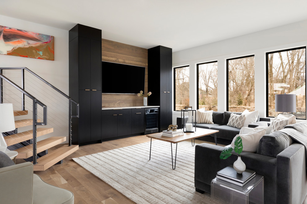 Свежая идея для дизайна: гостиная комната в современном стиле с белыми стенами, паркетным полом среднего тона, телевизором на стене и коричневым полом - отличное фото интерьера