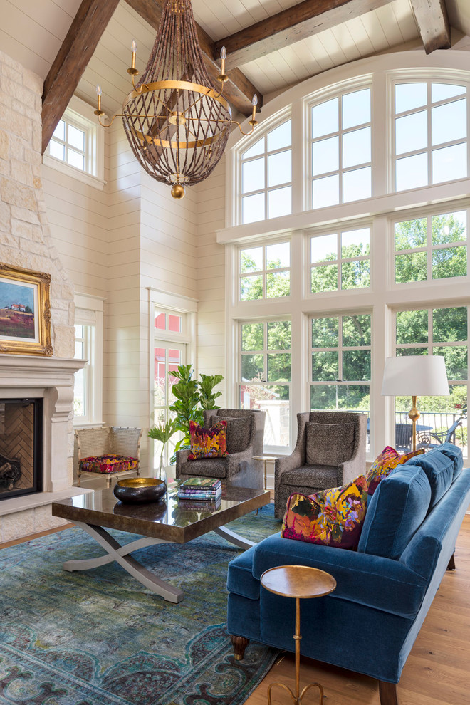 Repräsentatives Country Wohnzimmer mit beiger Wandfarbe, hellem Holzboden, Kamin, Kaminumrandung aus Stein und Steinwänden in Minneapolis