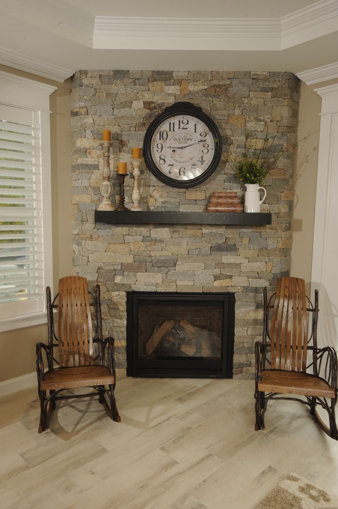 ポートランド(メイン)にあるトラディショナルスタイルのおしゃれなリビング (ベージュの壁、セラミックタイルの床、コーナー設置型暖炉、石材の暖炉まわり、テレビなし) の写真