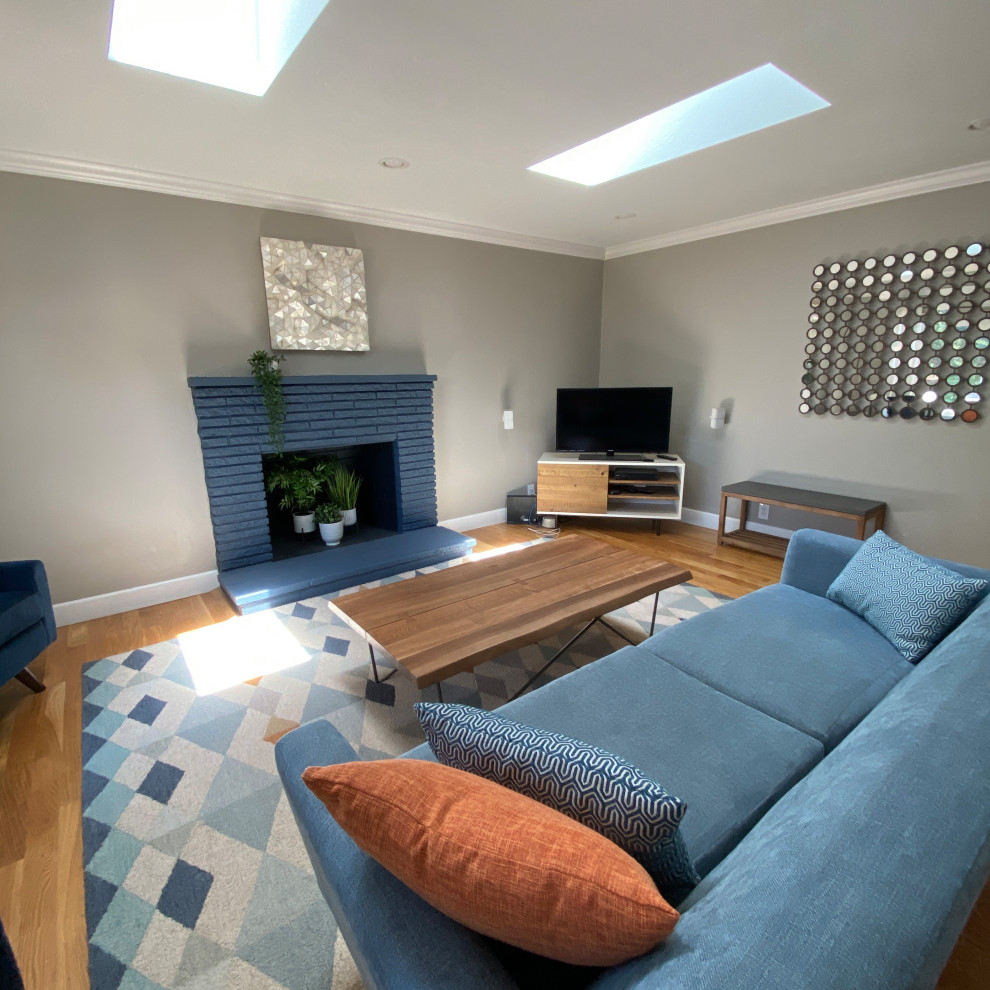 Aménagement d'un petit salon rétro fermé avec un mur gris, un sol en bois brun, une cheminée standard, un manteau de cheminée en brique, un téléviseur indépendant et un sol marron.