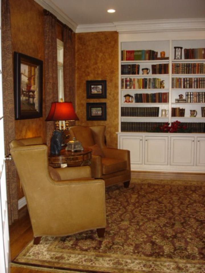 Идея дизайна: большая изолированная гостиная комната в стиле неоклассика (современная классика) с с книжными шкафами и полками, коричневыми стенами и темным паркетным полом