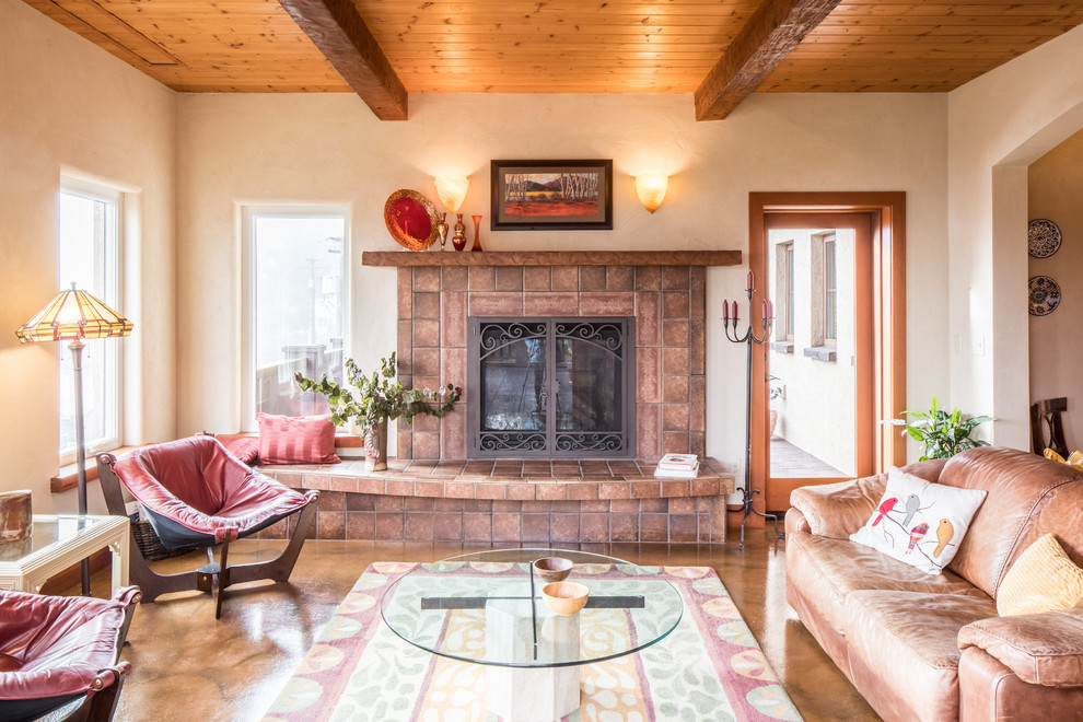 Источник вдохновения для домашнего уюта: открытая гостиная комната среднего размера в средиземноморском стиле с оранжевыми стенами, бетонным полом, стандартным камином, фасадом камина из плитки и коричневым полом