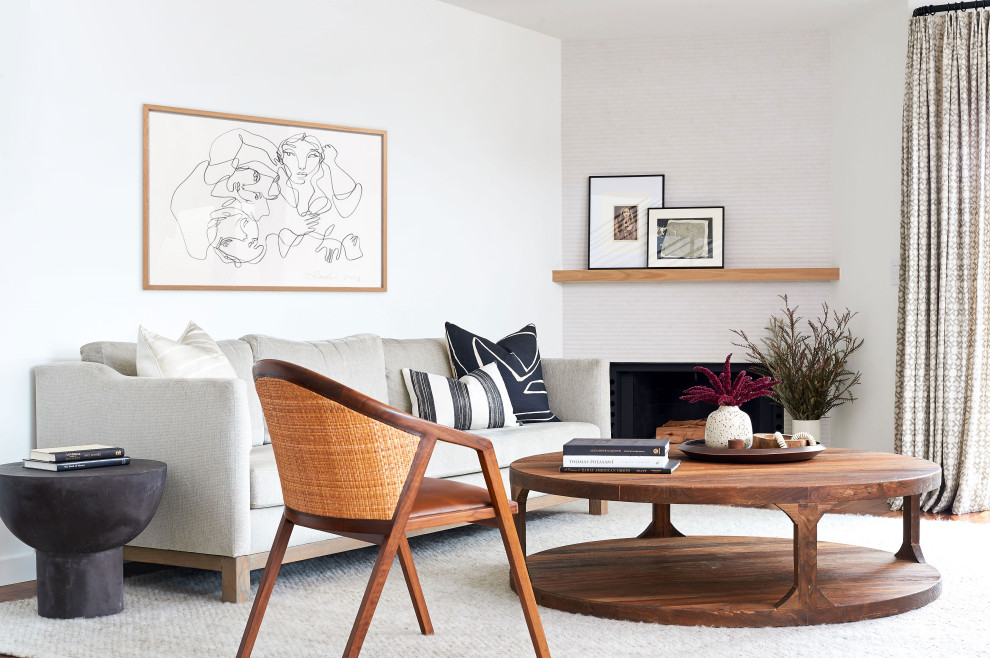 Cette image montre un salon design avec un mur blanc, un sol en bois brun, une cheminée standard et un sol marron.