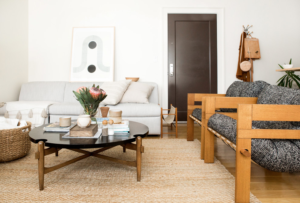 Mittelgroßes, Offenes Skandinavisches Wohnzimmer ohne Kamin mit weißer Wandfarbe, hellem Holzboden, freistehendem TV und beigem Boden in New York