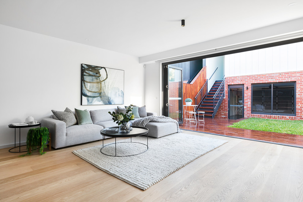 Photo of a modern formal open plan living room in Melbourne with white walls, light hardwood flooring and beige floors.