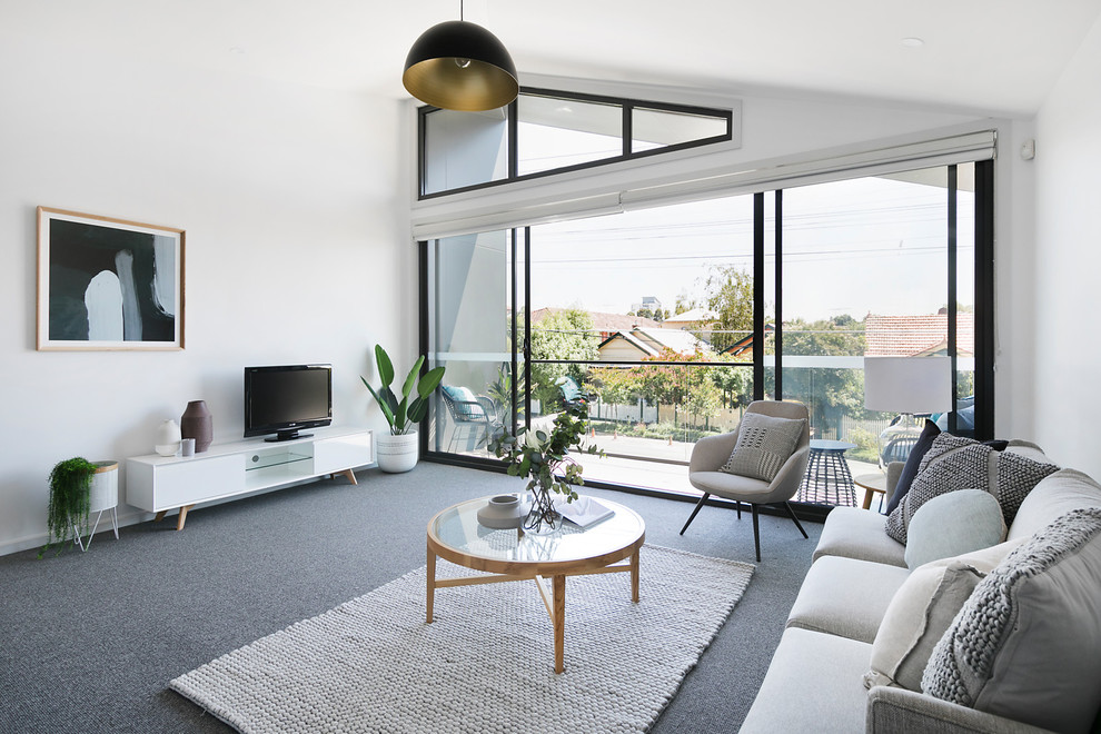 Photo of a contemporary formal living room in Melbourne with white walls, carpet, a freestanding tv and brown floors.
