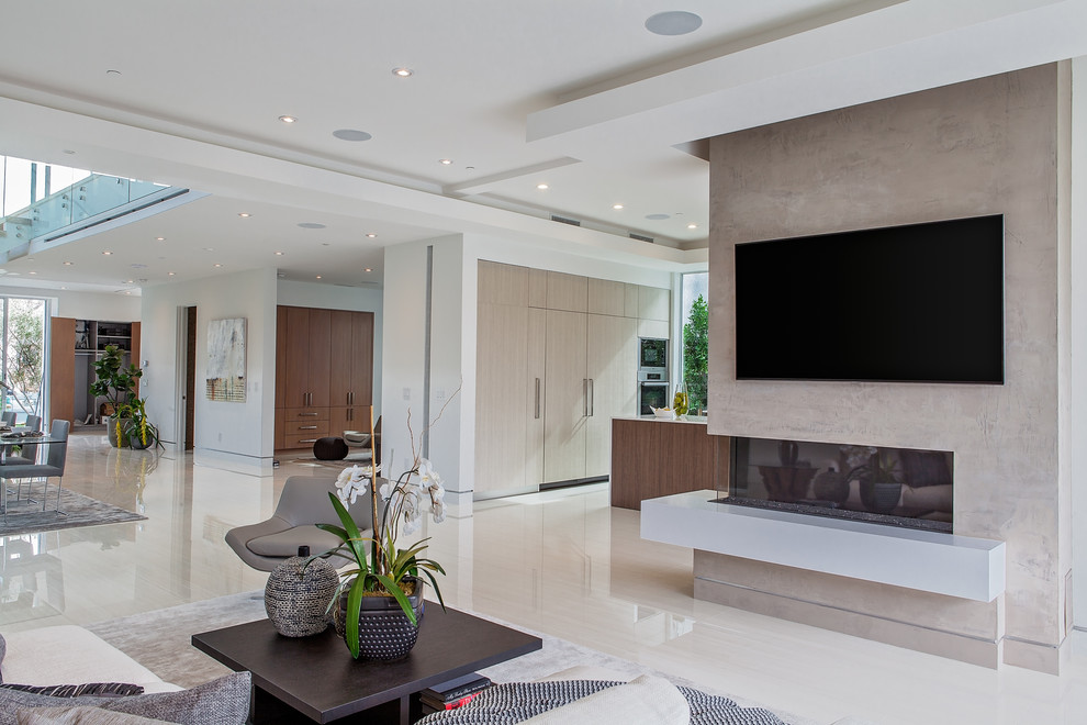 Пример оригинального дизайна: огромная парадная, открытая гостиная комната в стиле модернизм с белыми стенами, фасадом камина из бетона и телевизором на стене