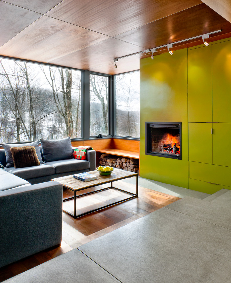 Пример оригинального дизайна: гостиная комната в современном стиле с зелеными стенами, паркетным полом среднего тона и стандартным камином