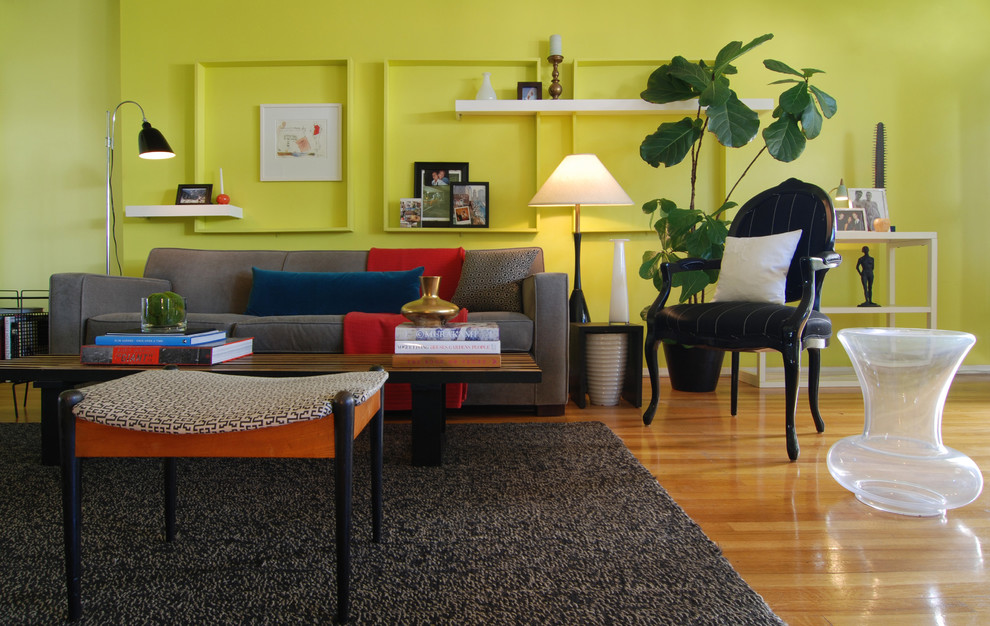 На фото: гостиная комната в стиле фьюжн с желтыми стенами и паркетным полом среднего тона