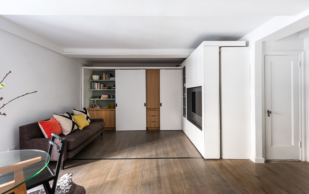 Immagine di un piccolo soggiorno moderno aperto con pareti bianche, pavimento in legno massello medio e parete attrezzata