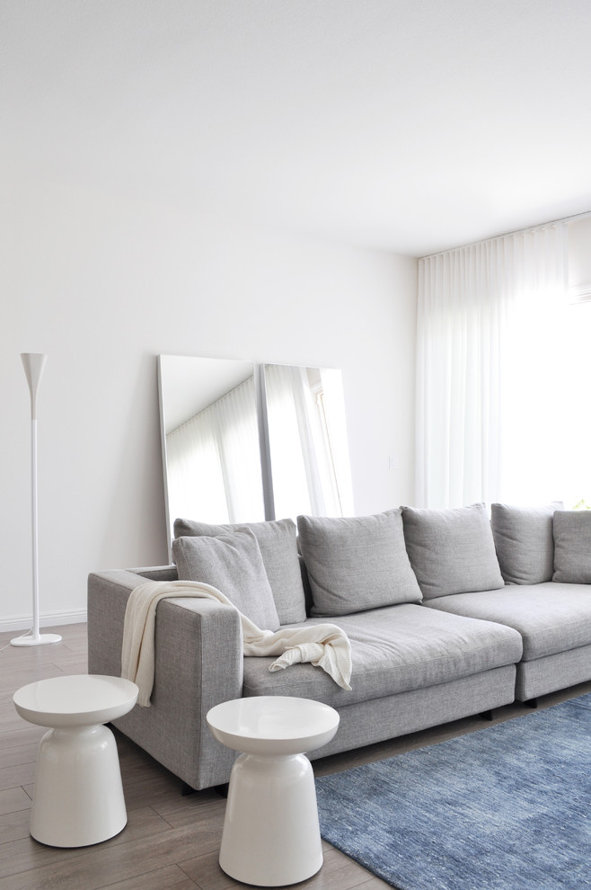 Foto di un soggiorno design di medie dimensioni e chiuso con sala formale, pareti bianche, parquet chiaro e TV a parete