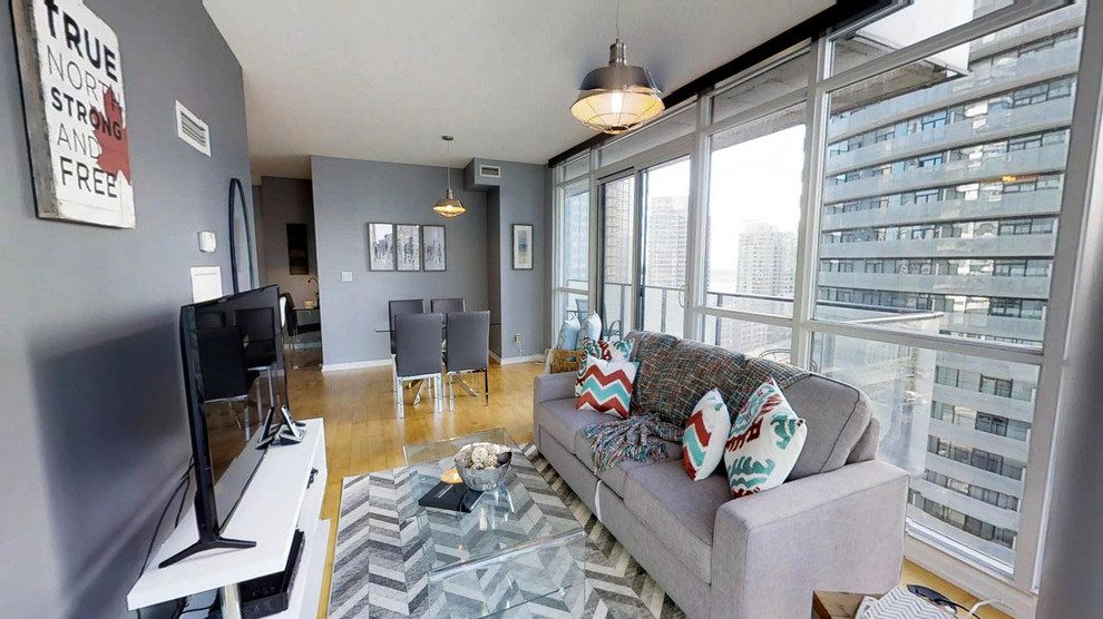 Kleines, Abgetrenntes Modernes Wohnzimmer ohne Kamin mit Hausbar, grauer Wandfarbe, Laminat, freistehendem TV und gelbem Boden in Toronto