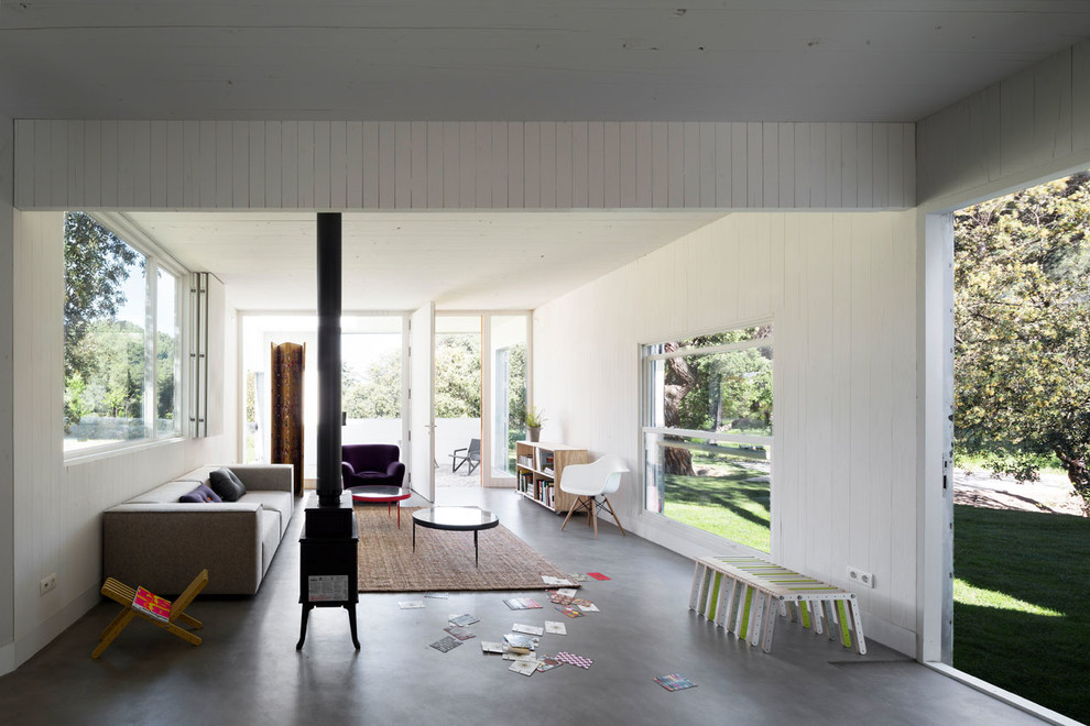 Modelo de salón para visitas abierto contemporáneo grande con paredes blancas, suelo de cemento y estufa de leña