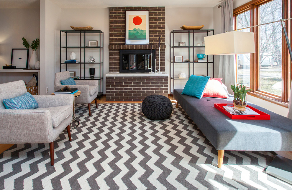 Идея дизайна: парадная, открытая гостиная комната в стиле ретро с серыми стенами, светлым паркетным полом и фасадом камина из кирпича