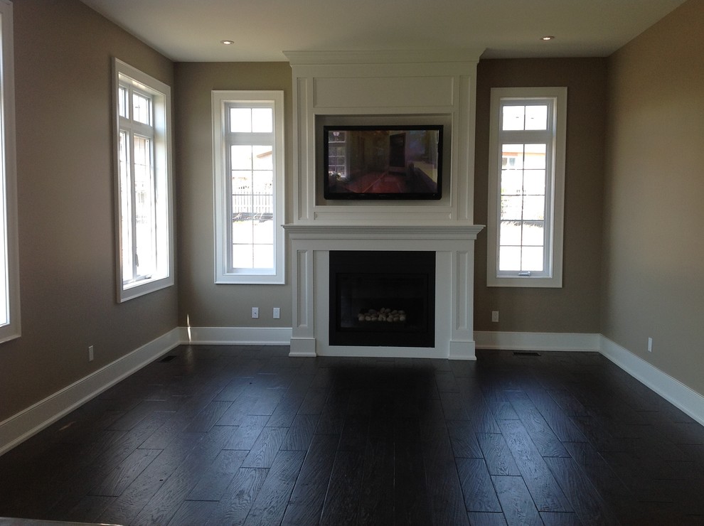 Design ideas for a large traditional formal enclosed living room in Toronto with a standard fireplace, a wooden fireplace surround, beige walls, dark hardwood flooring, a wall mounted tv and brown floors.