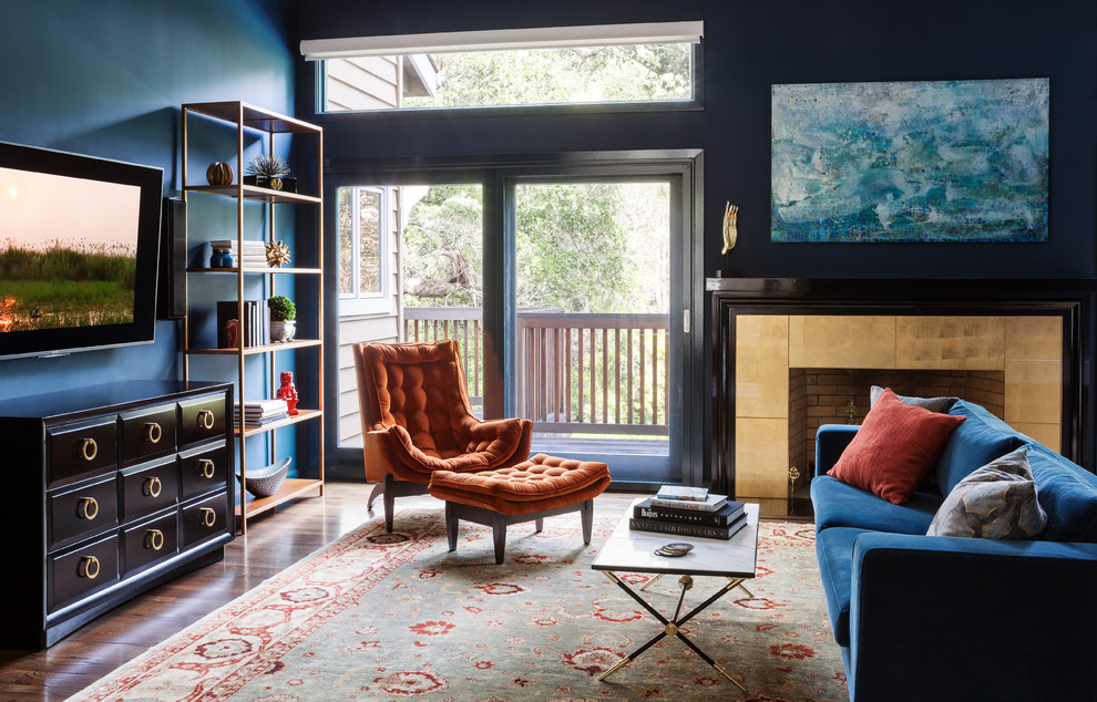 Modelo de salón para visitas cerrado bohemio grande con paredes azules, suelo de madera en tonos medios, todas las chimeneas, televisor colgado en la pared y marco de chimenea de baldosas y/o azulejos
