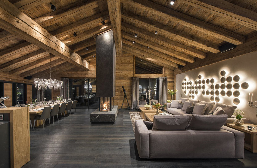Foto de salón abierto contemporáneo extra grande con suelo de madera oscura, chimenea de doble cara y marco de chimenea de hormigón
