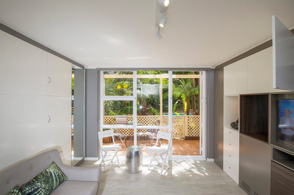 Пример оригинального дизайна: маленькая открытая гостиная комната в современном стиле с серыми стенами, светлым паркетным полом и отдельно стоящим телевизором без камина для на участке и в саду
