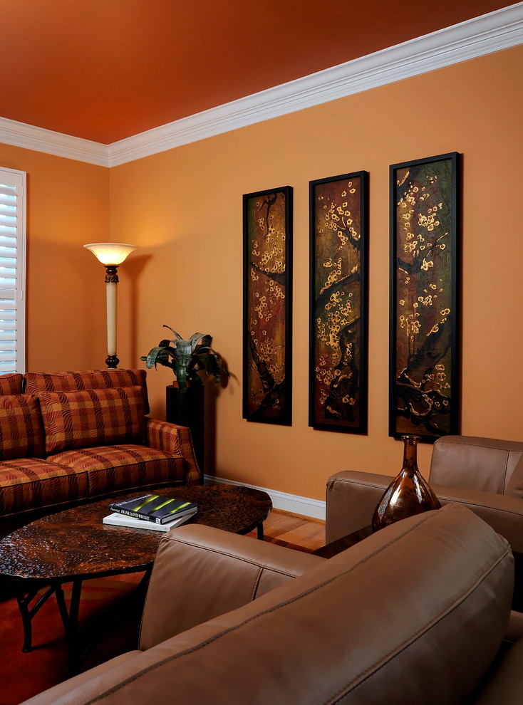 Immagine di un soggiorno classico di medie dimensioni e aperto con sala formale, pareti arancioni, pavimento in legno massello medio, nessun camino e nessuna TV