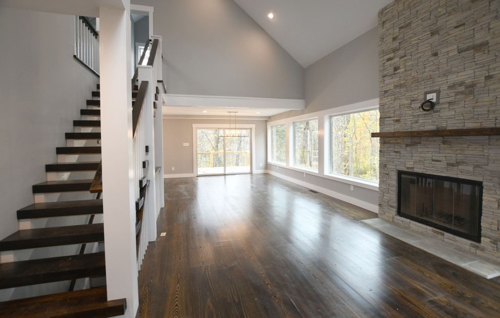 Inspiration for a mid-sized country open concept dark wood floor and brown floor living room remodel in New York with gray walls, a standard fireplace and a stone fireplace