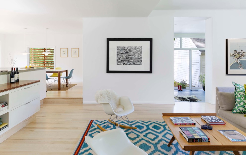 Modelo de salón para visitas abierto minimalista sin chimenea con paredes blancas, suelo de madera clara y suelo marrón
