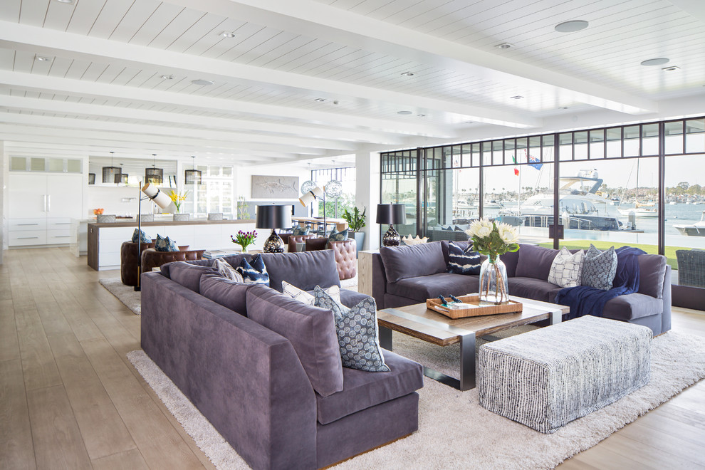 Immagine di un soggiorno stile marino aperto con pareti bianche, parquet chiaro e pavimento beige
